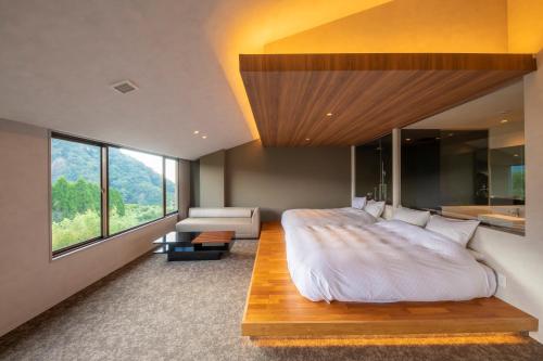 a bedroom with a large bed and a large window at The ACONCAGUA RESORTS in Minami Aso