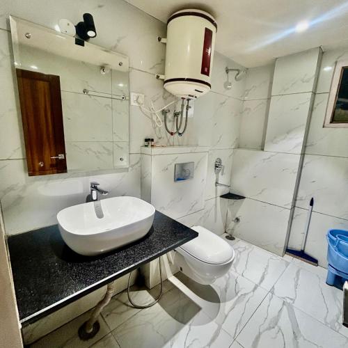 a white bathroom with a sink and a toilet at Kaisha Himalayan View in Shimla