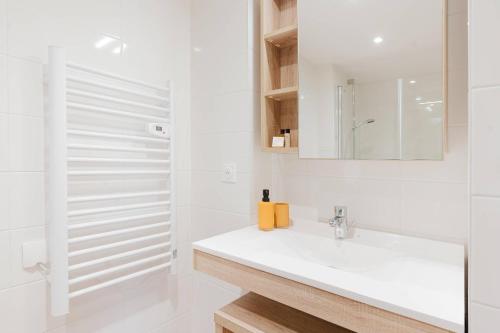 a white bathroom with a sink and a mirror at Quality Aparthotel Quiberon in Quiberon