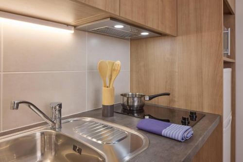 a kitchen counter with a sink and a stove at Quality Aparthotel Perpignan Prestige in Perpignan