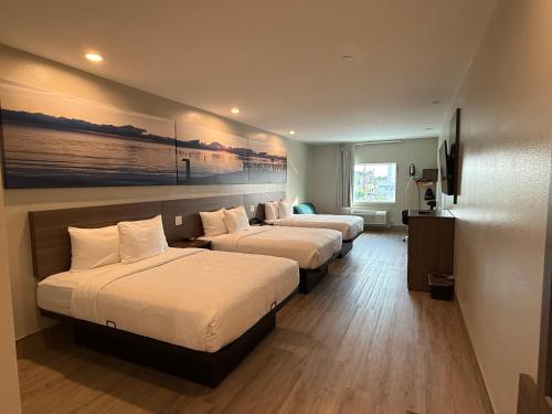 a hotel room with three beds and a painting on the wall at Clarion Pointe Port Lavaca in Port Lavaca