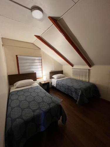 two beds in a room with a attic at Departamento la espiga in Chaitén