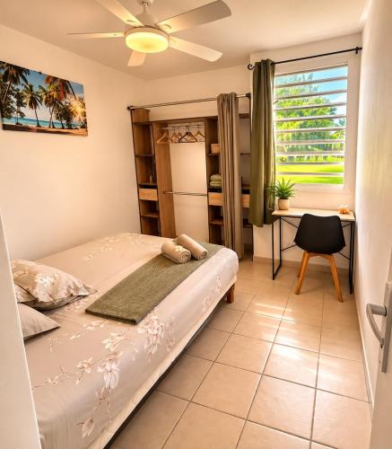 a bedroom with a bed and a desk and a window at Le Cocon de Mont-Vert in Le Robert