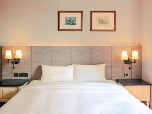 a bedroom with a large white bed with two lamps at Rhyme&Time Hotel in Kaohsiung
