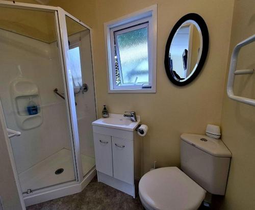 a bathroom with a toilet and a sink and a mirror at Waikanae Accommodation Studio B&B in Waikanae