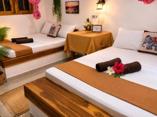 two beds in a room with two tables at The Ramp Udawalawe in Udawalawe