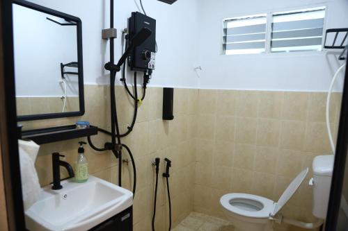 a bathroom with a toilet and a sink and a mirror at Penyu Bari in Setiu