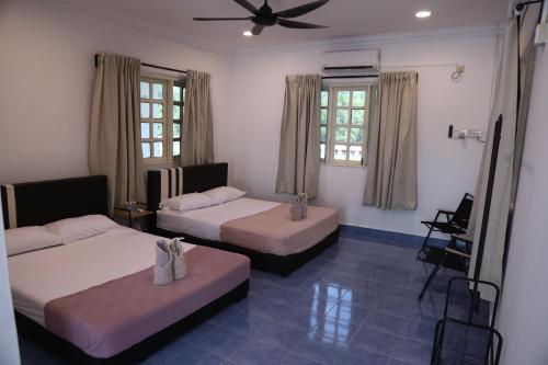 a bedroom with two beds and a ceiling fan at Penyu Bari in Setiu