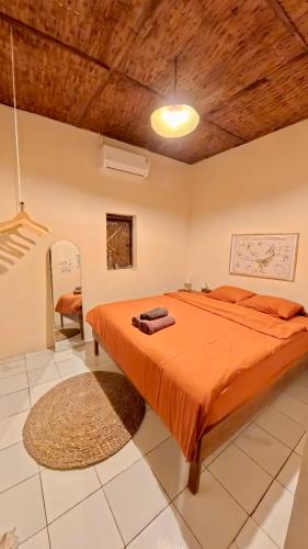a bedroom with a bed with an orange comforter at Alianna Homestay in Karimunjawa