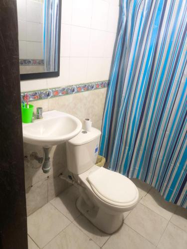 a bathroom with a white toilet and a sink at Posada El Encanto in Nuquí
