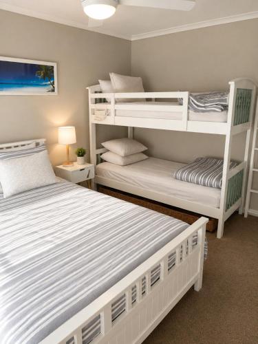 two white bunk beds in a small room at Coastal Cottage in Saint Leonards