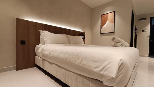 a bedroom with a large white bed with a wooden headboard at sohho Hotel in Cukai