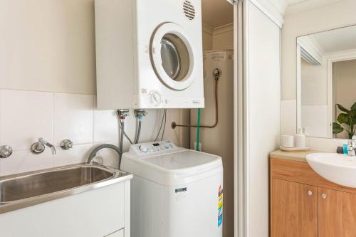 a small bathroom with a sink and a washing machine at Seachange Apartments Merimbula in Merimbula