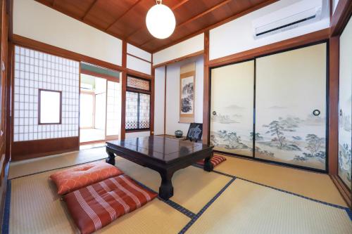 a room with a table and a couch and windows at 湊の宿あまね in Hitachinaka