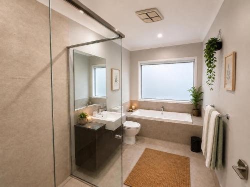 a bathroom with a tub and a toilet and a sink at Guest House near theme parks in Pimpama