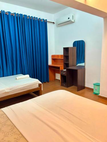 a room with two beds and a blue curtain at Himo Guest Inn in Dehiwala