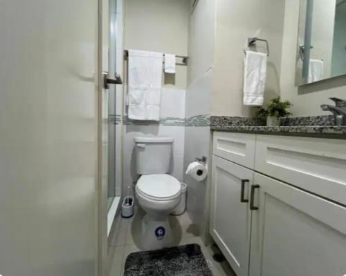 a white bathroom with a toilet and a sink at Royal Estate in Portmore