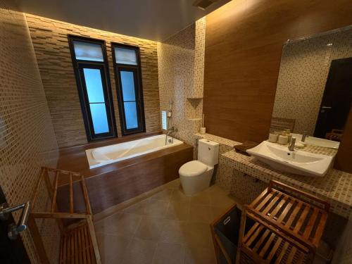 a bathroom with a tub and a toilet and a sink at Villa Tara Khaolak in Khao Lak