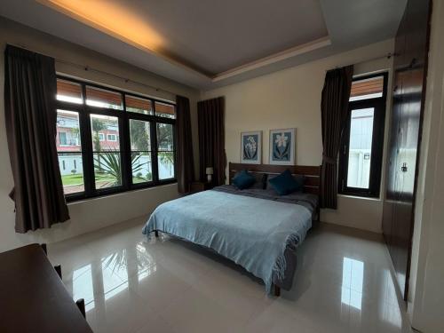 a bedroom with a bed with blue sheets and windows at Villa Tara Khaolak in Khao Lak