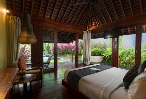 a bedroom with a bed and a desk and a window at Temuku Ubud Villas in Ubud