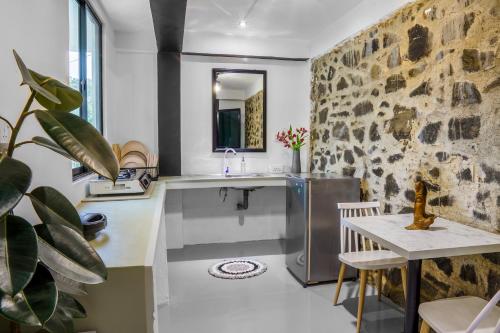 a kitchen with a sink and a stone wall at Rock View Cottage in Ella
