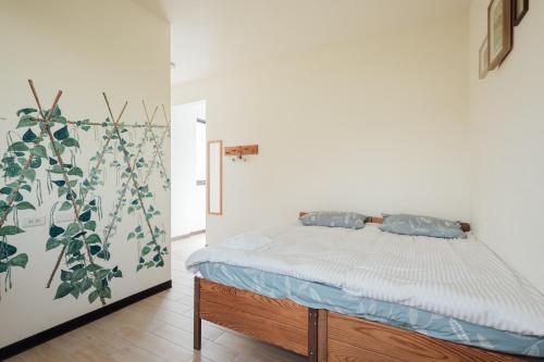 a bedroom with a bed and a plant on the wall at Tree House Café & Homestay in Tongluo