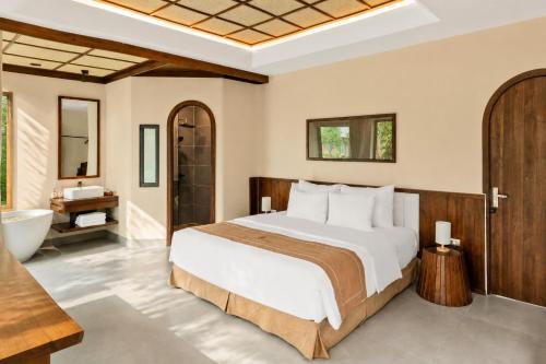 a bedroom with a bed and a bathtub and a sink at Cuc Phuong Tropical Villas in Thượng Sung