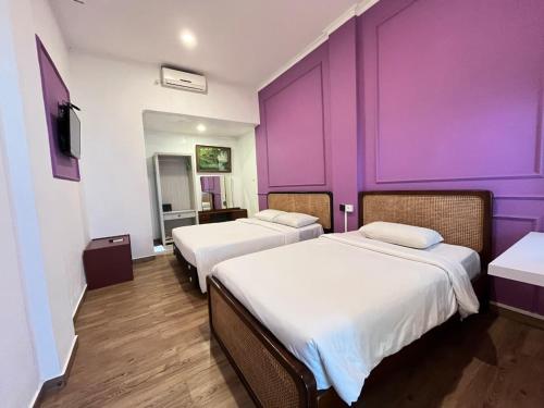 two beds in a room with purple walls at Riche Heritage Hotel Kayutangan Malang in Malang