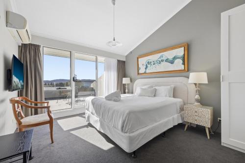 a bedroom with a white bed and a large window at Horizons 404 in Jindabyne