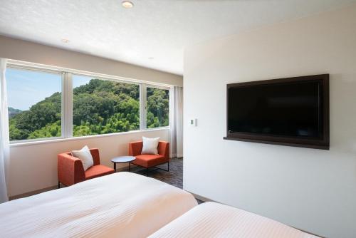 a hotel room with a bed and a flat screen tv at Hotel Vista Matsuyama in Matsuyama