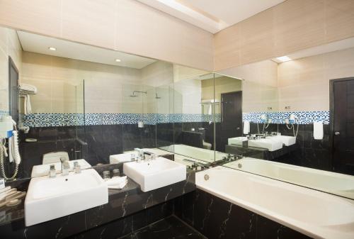 a bathroom with three sinks and a large mirror at Swiss-Belhotel Kendari in Kendari