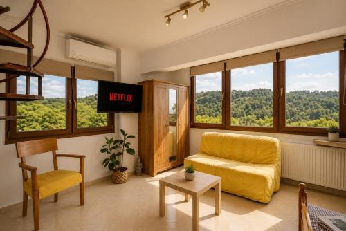 a living room with a yellow chair and a television at Studio Acropolis Serres Parking EV Next to Center in Serres