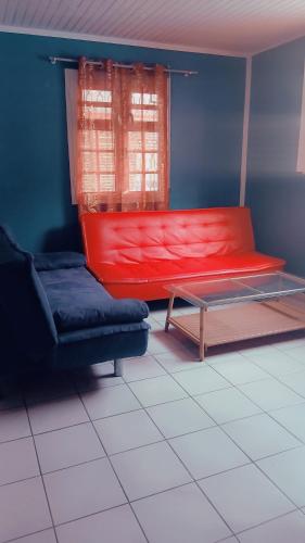 a living room with a red couch and a window at La vallée verte Martinique in Le Lamentin