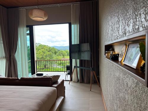 a bedroom with a bed and a balcony with a view at The BROWN PAI in Pai
