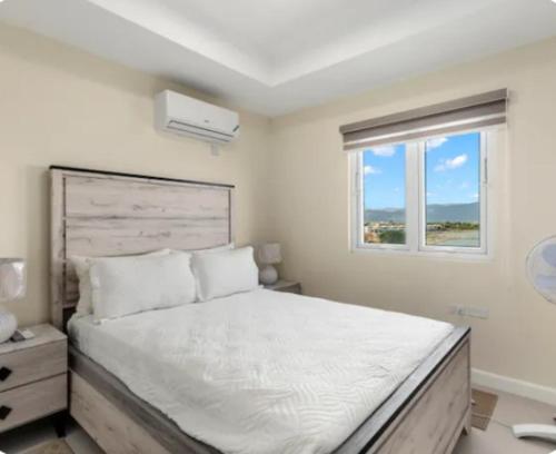 a bedroom with a large white bed with a window at Deluxe suite in Portmore