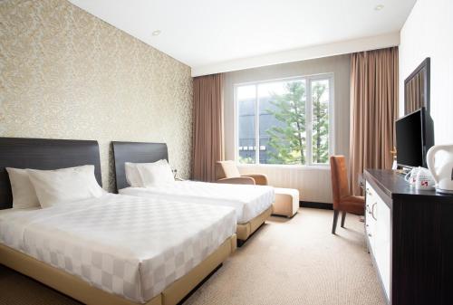 a hotel room with two beds and a television at Swiss-Belhotel Kendari in Kendari