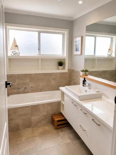 a bathroom with a sink and a tub and a window at Coastal Cottage in Saint Leonards