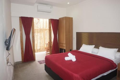 a bedroom with a red bed with two white towels on it at Two Brothers Guesthouse in Legian