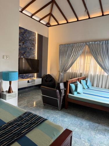 a bedroom with two beds and a flat screen tv at Natures Bliss Holidays in Ja-Ela