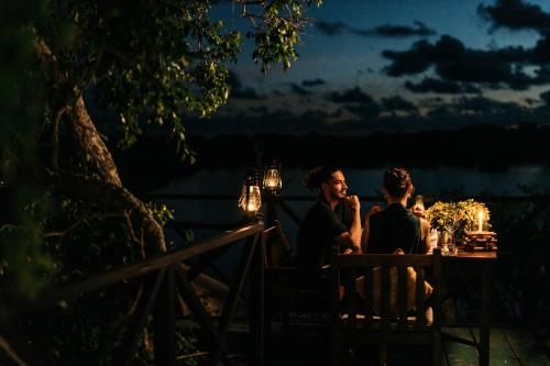 a man and a woman sitting at a table at night at Cinnamon Wild Yala in Yala