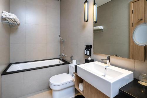 a bathroom with a sink and a toilet and a bath tub at Mangkuluhur Residences by Lorin in Jakarta