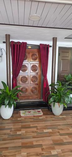 a room with two potted plants and a wooden cabinet at SK Guest House in Jaffna