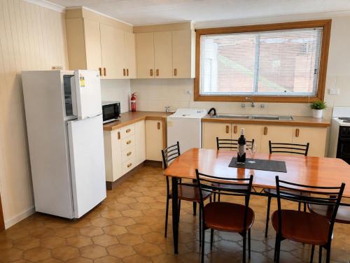 a kitchen with a table and a white refrigerator at Quaint Hideaway in Portarlington