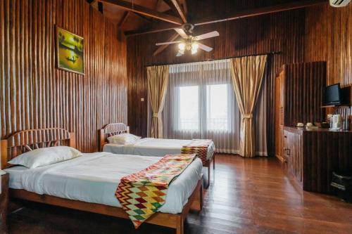 a bedroom with two beds and a ceiling fan at de Bintan Villa in Tenaga