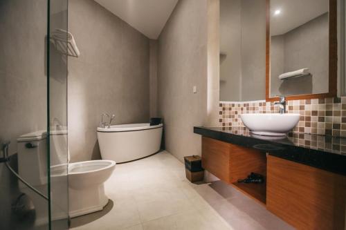a bathroom with a toilet and a sink and a tub at de Bintan Villa in Tenaga