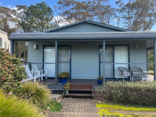 a blue house with two chairs on a porch at Bawley Beach Bungalow in Bawley Point