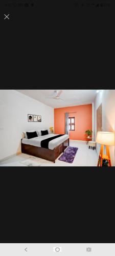 a bedroom with a large bed and an orange wall at New Stay Hotel in Gurgaon