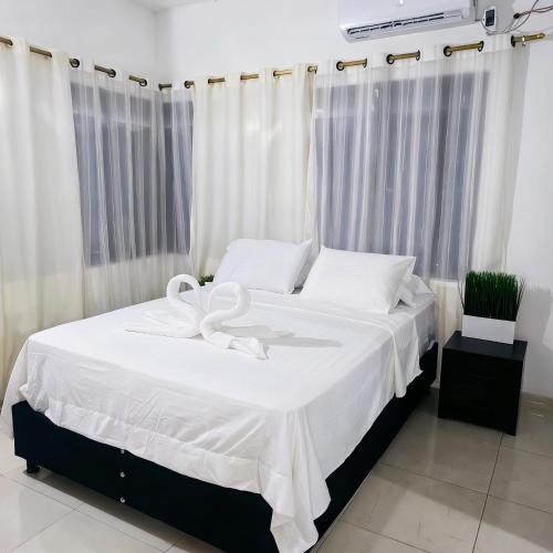 a bedroom with a white bed with a ribbon on it at Hotel Montserrat in Valledupar