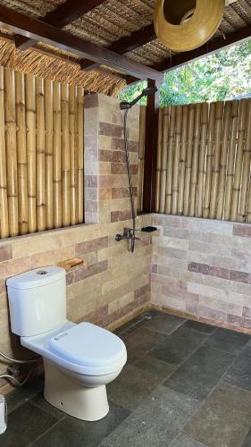 a bathroom with a toilet and a shower at Mango Garden Villas in Sekongkang Bawa