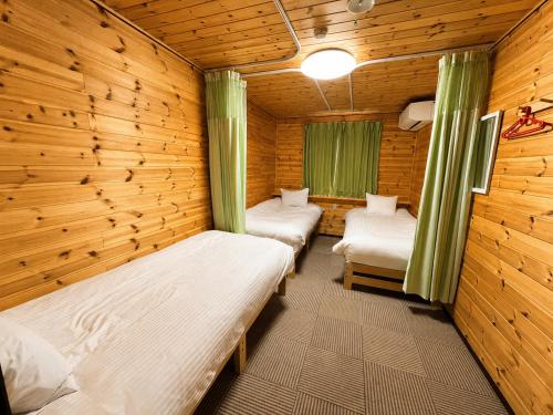 a room with three beds in a log cabin at Meteor Garden in Hakuba